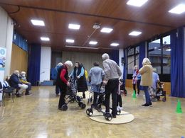 Aktionstag sicher unterwegs mit dem Rollstuhl und Rollator Eine Gruppe älterer Menschen mit Rollatoren fährt über Holzbretter.