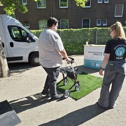 Eine Frau vom Kreissportbund erklärt einem Mann mit Rollator die Nutzung des Rollators.