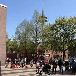 Viele Menschen stehen auf einem Schulhof.