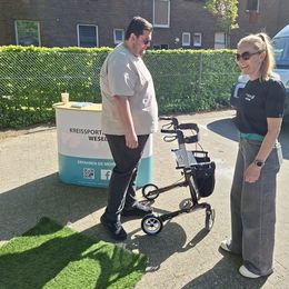 Zwei Personen stehen vor einem Infostand mit Aufdruck "Kreissportbund Wesel e.V.". Der Mann hat einen Rollator.