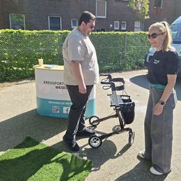 Mann mit Rollator vor Infostand mit Aufschrift "KREISSPORTBUND WESEL E.V." und Frau mit Team-T-Shirt