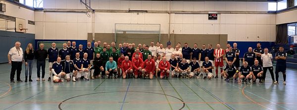 Gruppenfoto von mehreren Walking-Footballmannschaften, Schiedsrichtern und Ehrengästen in einer Sporthalle.