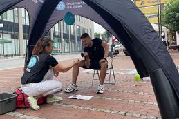 Ein Mitarbeiter des Kreissportbundes trainiert mit einer Hantel seinen Bizeps, während eine Mitarbeiterin des Kreissportbundes ihm dabei Tipps gibt.