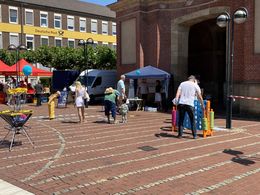 Einige Menschen testen bei Sonnenschein diverse Spiele vor dem Stand des Kreissportbundes. Im Hintergrund ist das Berliner Tor in Wesel zu sehen.