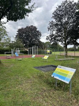 Alle Stationen eines Outdoorparcours sind zu sehen, im Vordergrund ein im Boden eingebautes Trampolin.