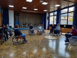 Aktionstag sicher unterwegs mit dem Rollstuhl und Rollator Mehrere Menschen in Rollstühlen stehen in einer Turnhalle.